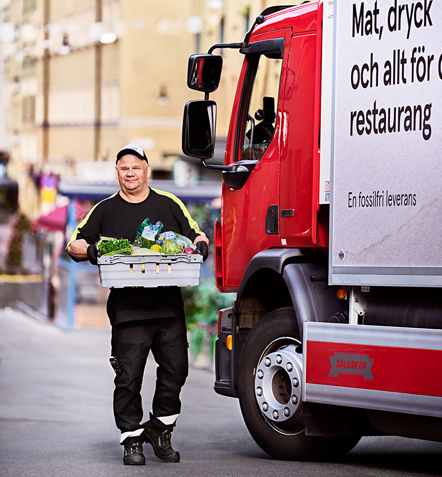Chaufför från Menigo står vi lastbil med låda med mat. 