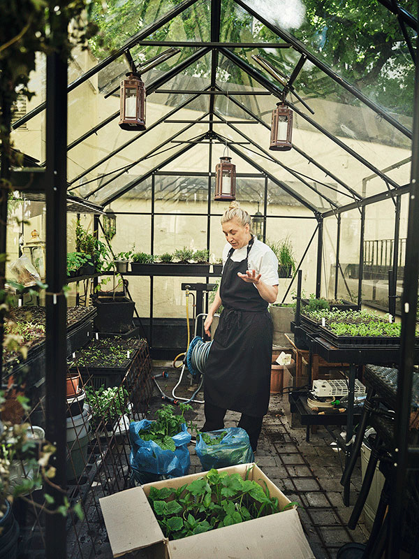 Tea Malmegård bland sina odlingar i växthuset.