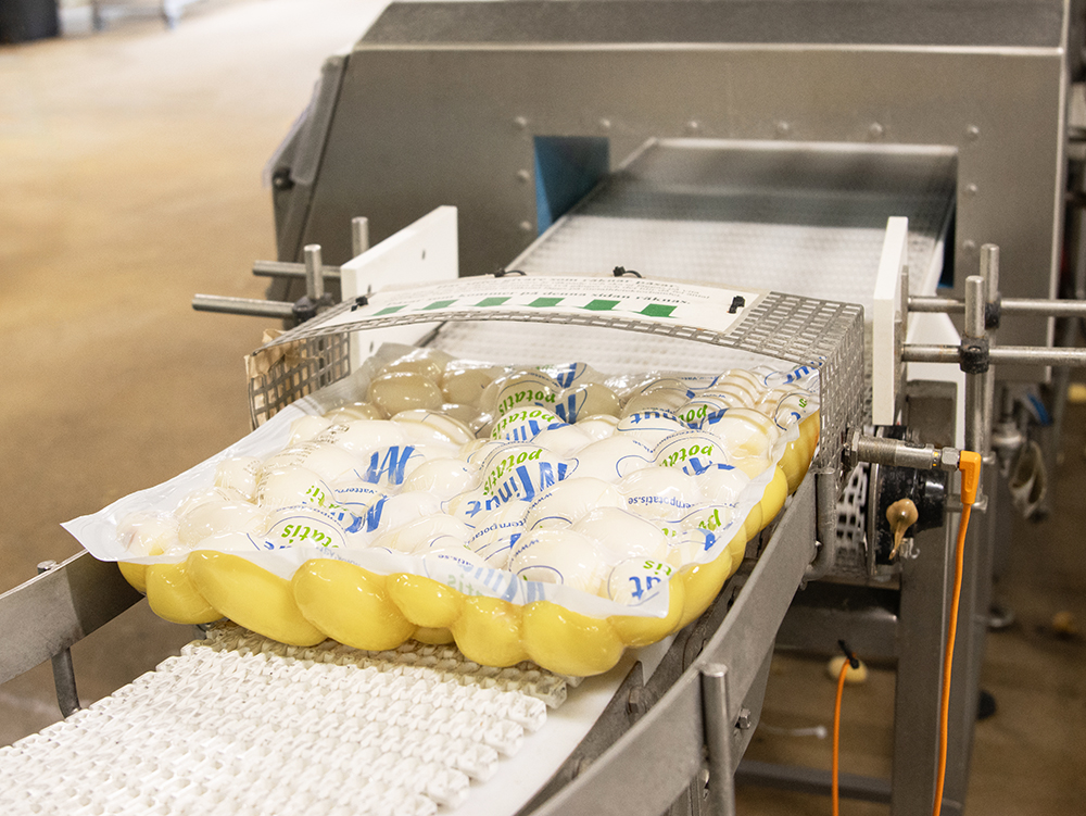 Förpackad potatis som åker på ett rullband i produktionsmiljö